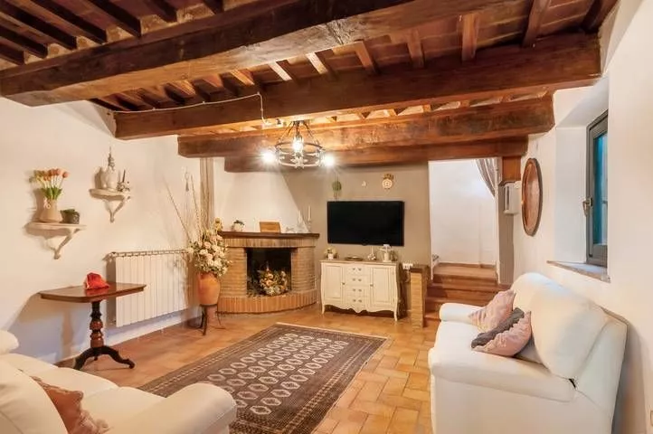 Cozy living room with fireplace and wooden beams at Podere Settefrati apartment