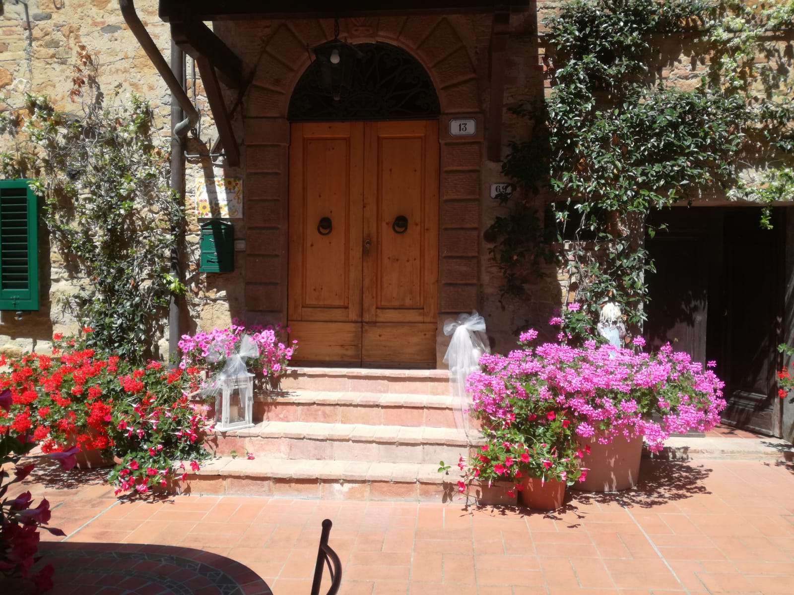 Main entrance of Podere Settefrati decorated with colorful flowers and stone walls in Tuscany