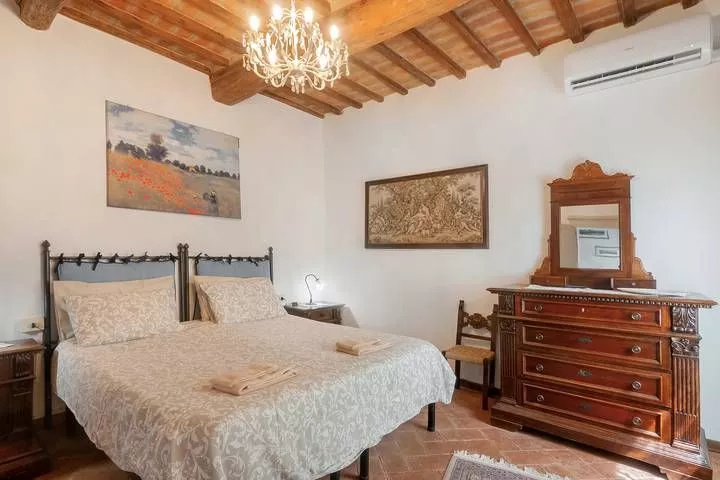 Master bedroom with chandelier and wooden furniture at Podere Settefrati farmhouse
