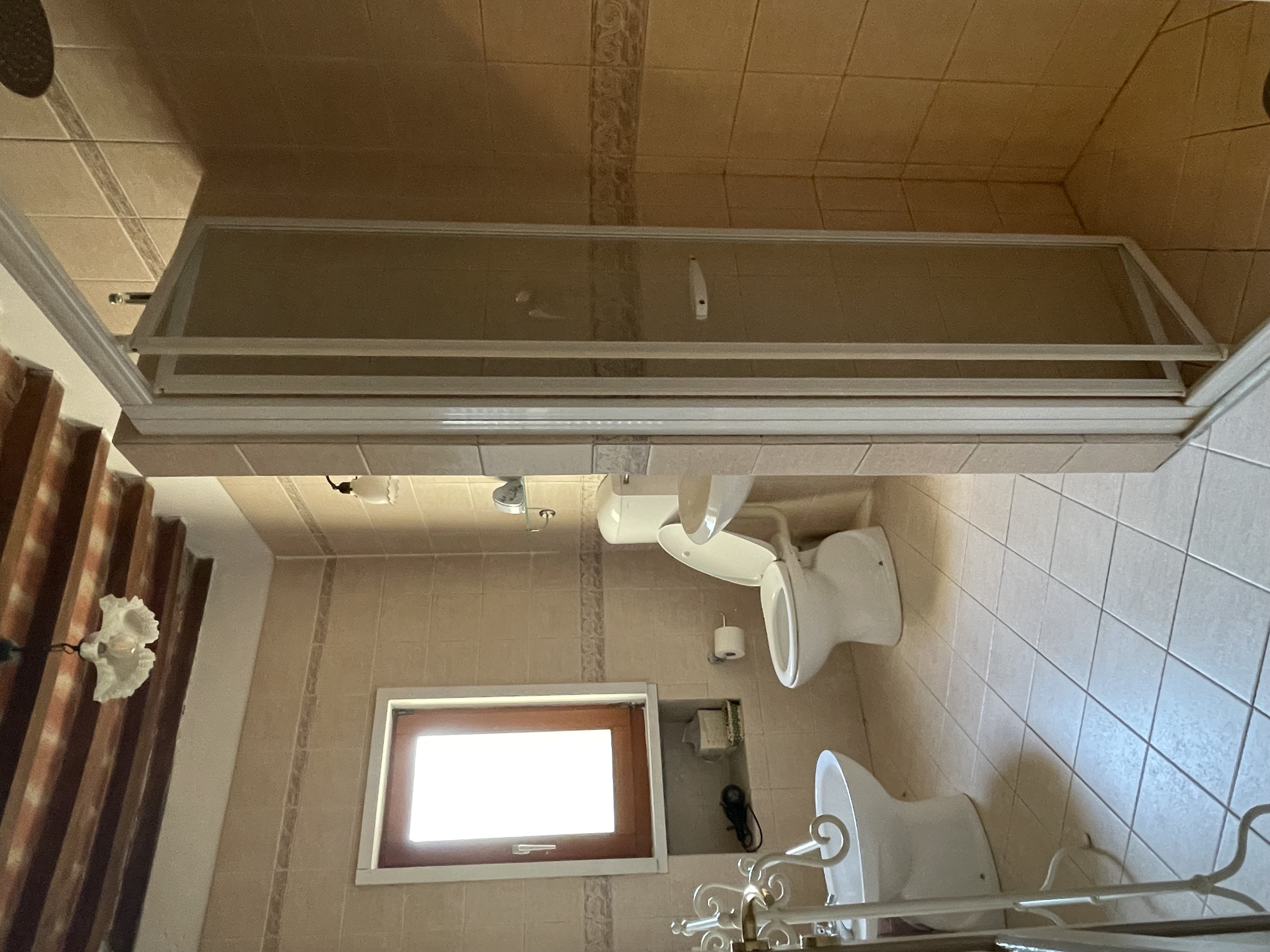 Bathroom with shower and wooden beam ceiling inside Podere Settefrati farmhouse in Tuscany