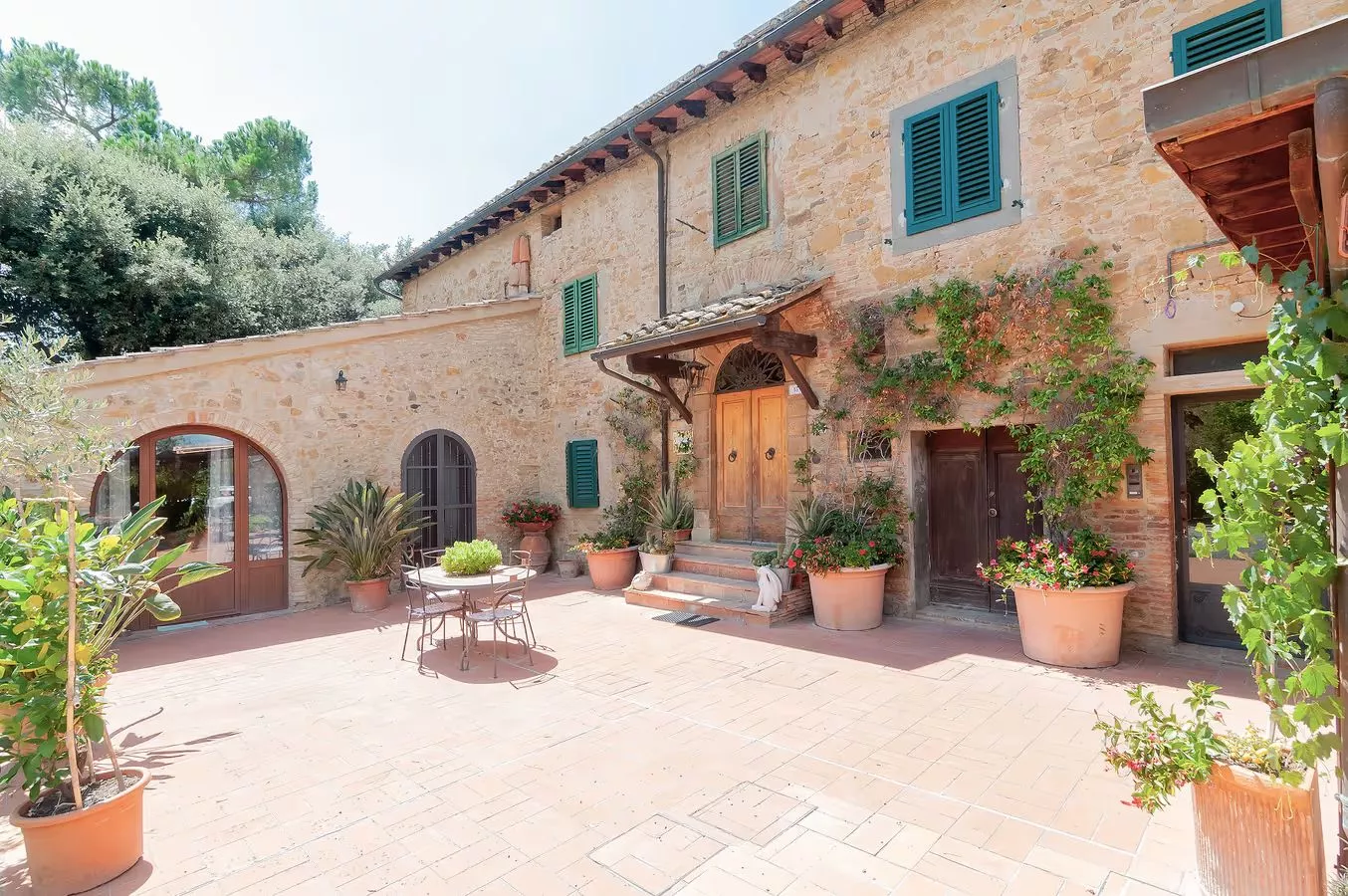 Courtyard of Podere Settefrati, traditional Tuscan farmhouse with stone walls, terracotta floor and potted plants in Montaione