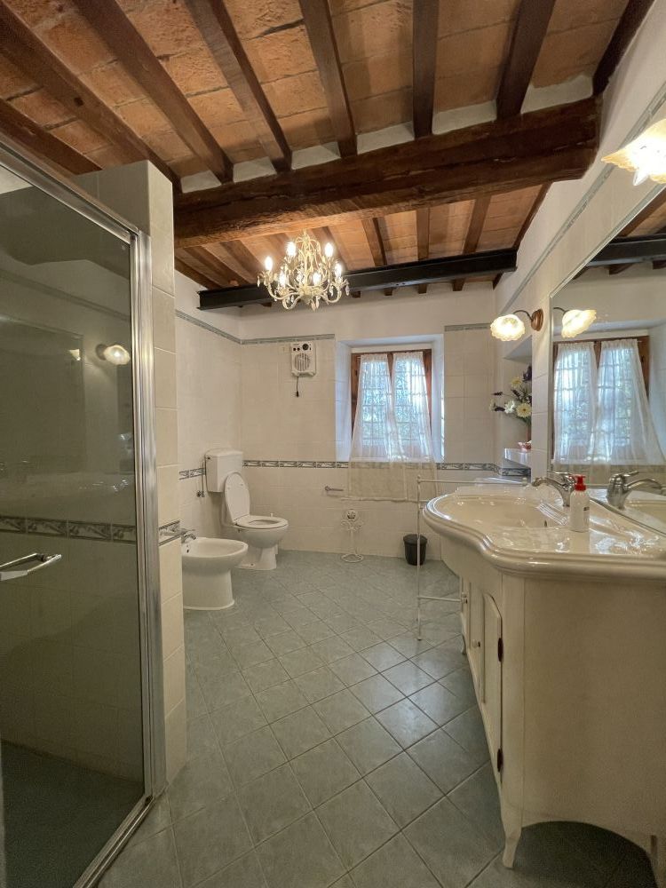Rustic Tuscan bathroom with wooden beams and double sink at Podere Settefrati farmhouse