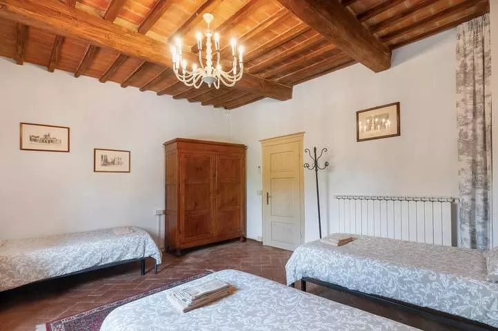 Spacious twin room with wooden ceiling and chandelier at Podere Settefrati Tuscany